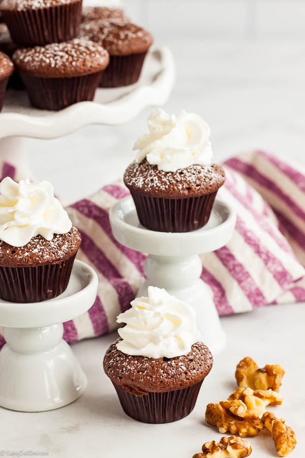 Close up image of mini brownies topped with whipped cream and dusted with powdered sugar. 