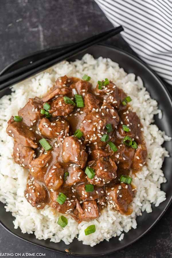 Close up of beef teriyaki over rice on a plate.