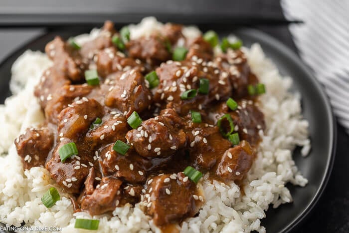 Close up of beef teriyaki over rice on a plate.