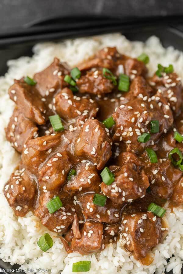 Close up of beef teriyaki over rice on a plate.