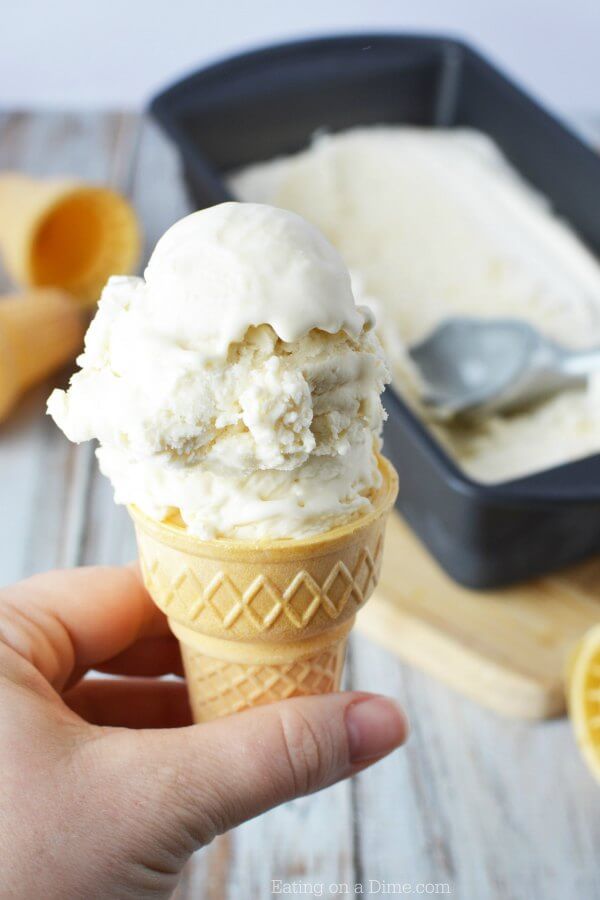 Homemade vanilla ice cream in a loaf pan with an ice cream scoop scooping out a portion of the ice cream.  