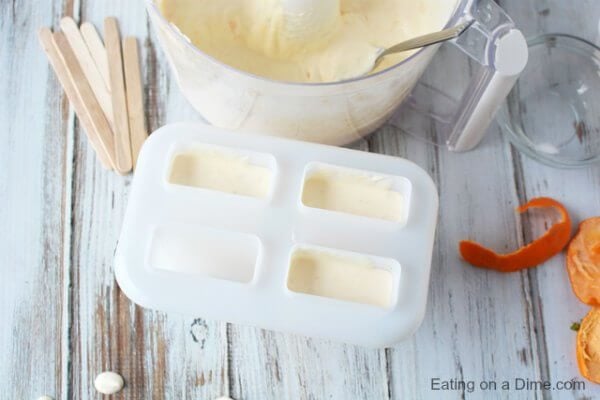 Close up image of blended ingredients being placed in the popsicle molds. 