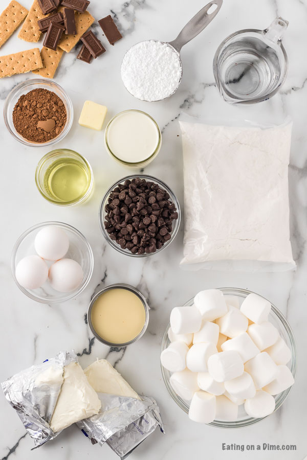 Ingredients needed - white cake mix, marshmallows, chocolate chips, butter, sweetened condensed milk, cream cheese, powdered sugar, cocoa powder, heavy whipping cream, graham crackers, chocolate, marshmallows