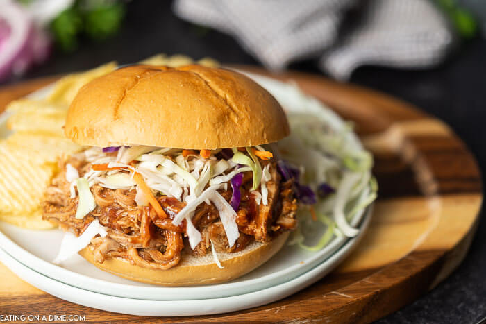 Try this Crock pot Pulled Pork Sandwich Recipe for a delicious and quick dinner idea. Crock pot pulled pork recipe is tender and packed with flavor! The sauce is tangy and so good! Your family will love pulled pork crock pot recipe. It is the best pulled pork sandwiches! Make Pulled pork sandwiches slow cooker today! #eatingonadime #crockpotrecipes #porkrecipes 