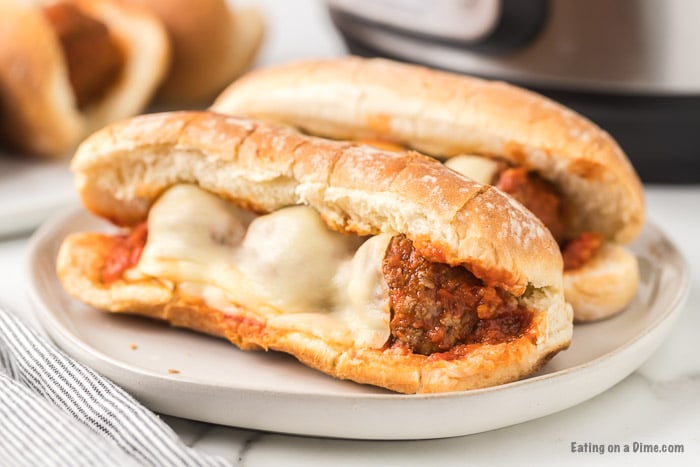 Close up image of two meatball subs on a white plate. 