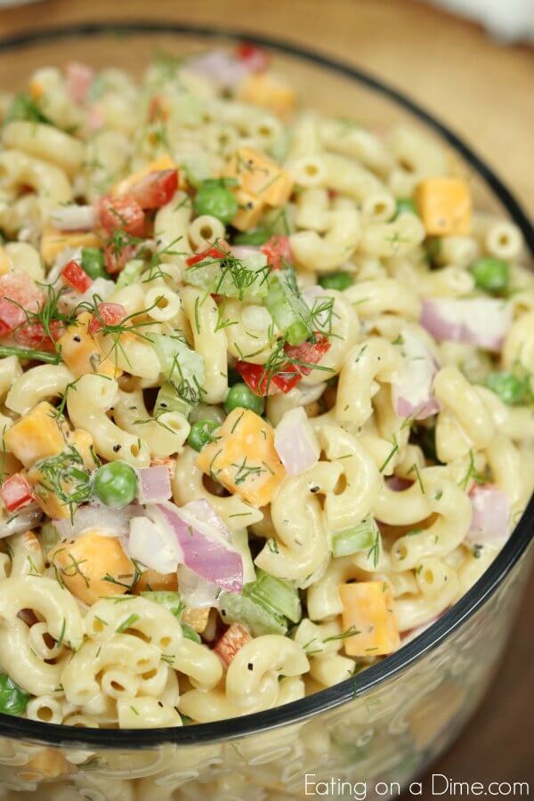 This Easy Macaroni Salad recipe is the perfect side dish to bring to Summer BBQ's, parties and more! Easy macaroni salad is loaded with veggies, cheese and more. You will love the creamy dressing in Macaroni salad recipe. Try this Pasta salad with mayo. Everyone will love this simple Elbow macaroni salad! Close up of Creamy Macaroni Salad in a large bowl topped with fresh dill