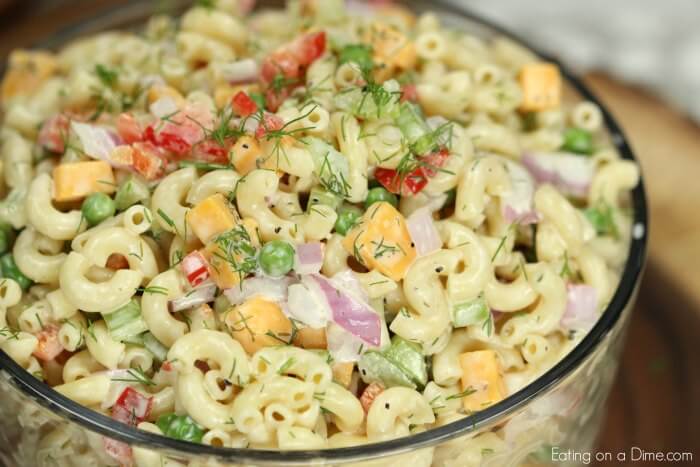 Close up of creamy Macaroni Salad in a large bowl topped with fresh dill 