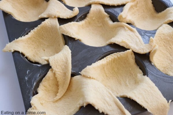 Crescent roll triangles in muffin tin.