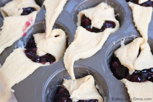 Crescent rolls being folded over to make pie bites.