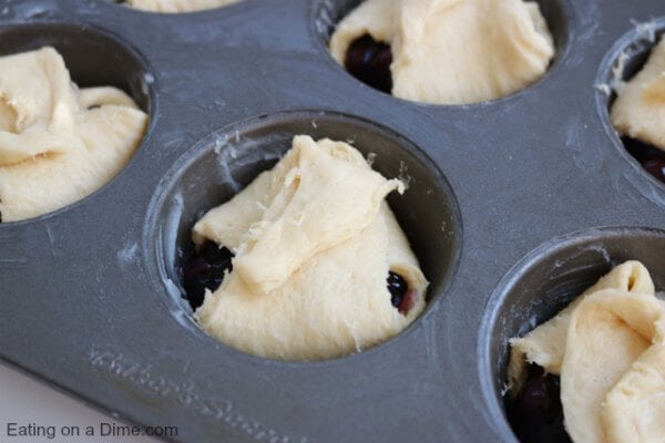 Muffin tin with blueberry pie bites ready to be baked. 