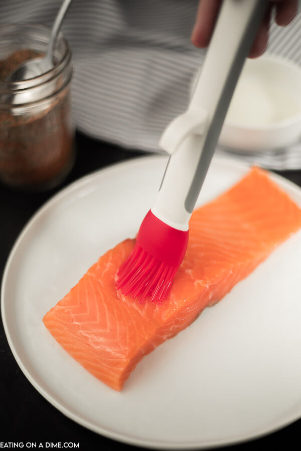 photo of salmon with oil being brushed on before cooking