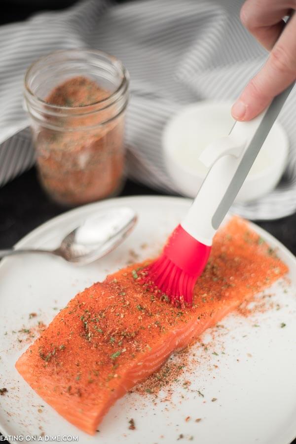 photo of salmon with spices being brushed on before cooking