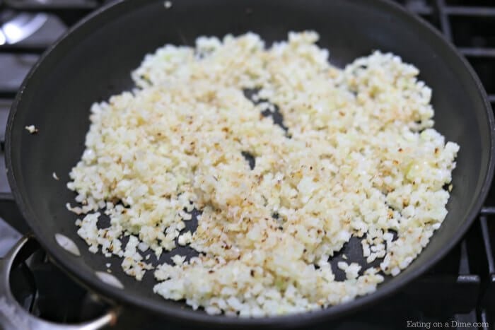 Cauliflower rice cooking in a skillet.