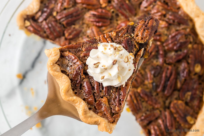 Close up image of a piece of Pecan Chocolate Pie with whipping cream on top. 
