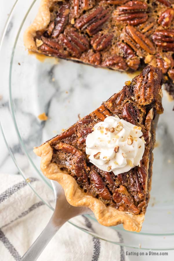 Close up image of a piece of Chocolate Pecan Pie with whipped topping. 