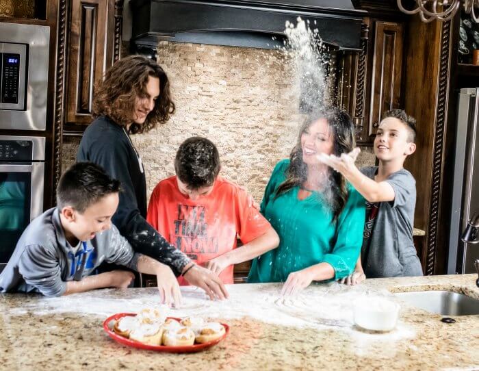 Carrie in her kitchen with her kids playing with flour in the countertop.  