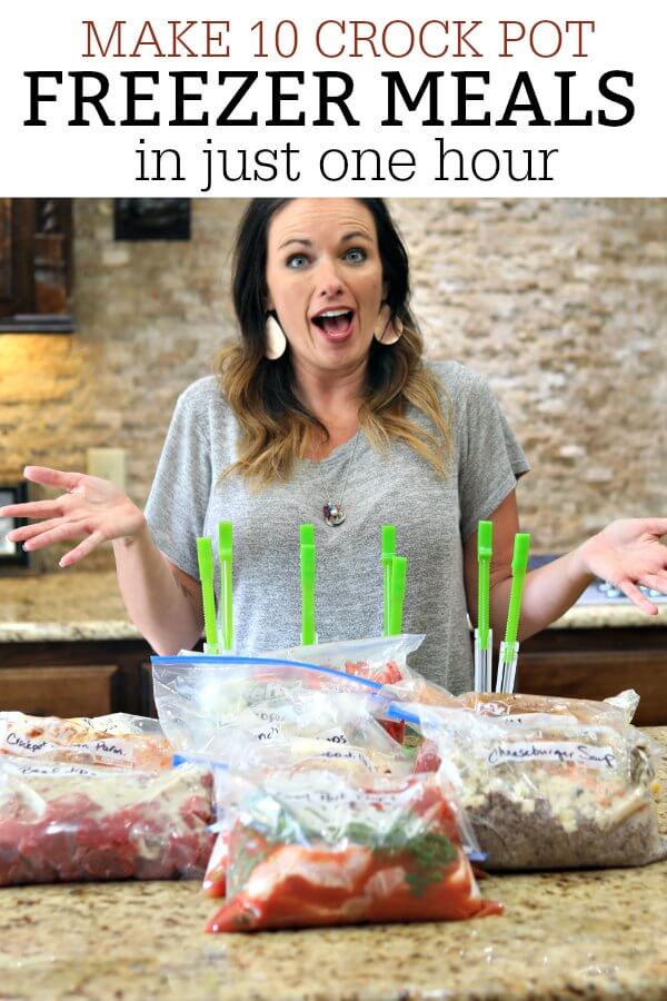 Have you been wanting to try freezer cooking? You can now make 10 crock pot freezer meals in just an hour! Plus, you will never have to menu plan again! Carrie standing in her kitchen in front of multiple freezer meals with a surprised look on her face.
