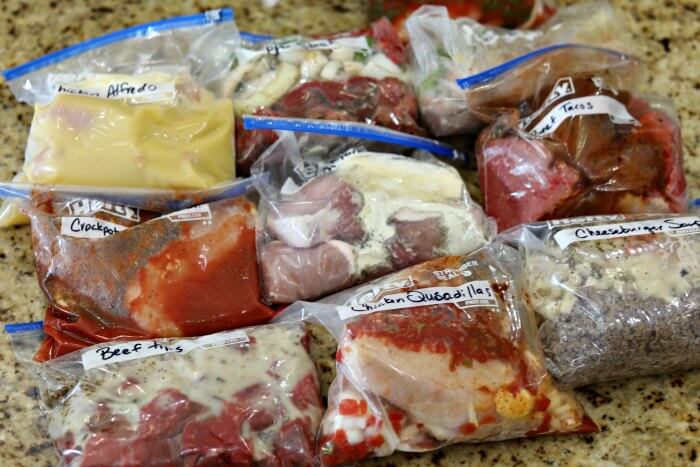9 Crock Pot Freezer Meals laid out on a countertop - Ready to be stored in the freezer.  
