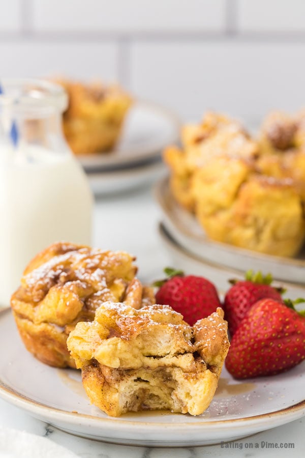 Close up image of French Toast Muffins on a white plate with a side of strawberries. 