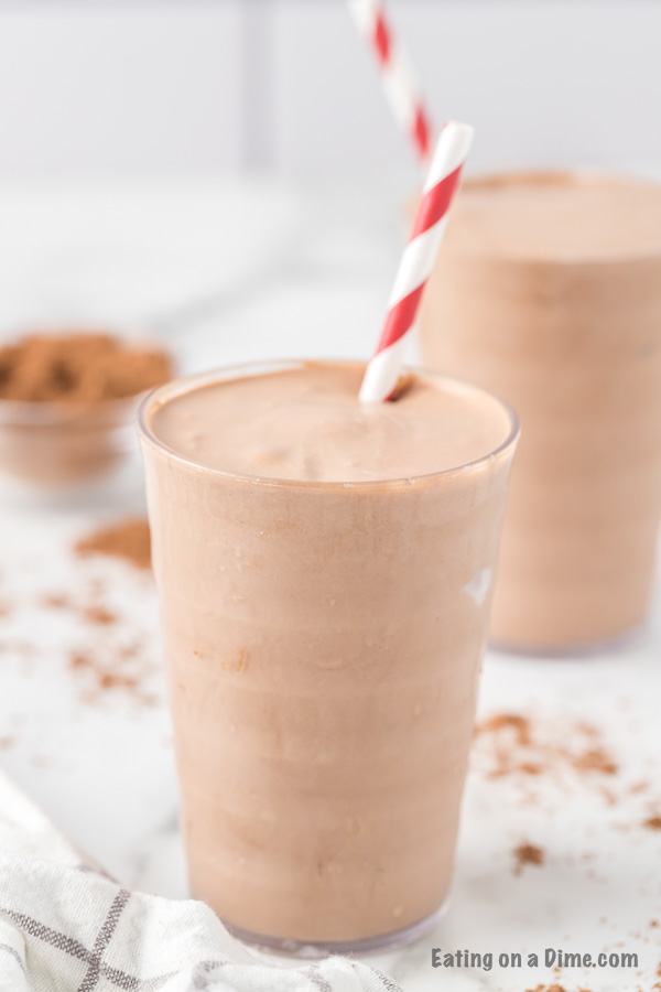 Close up image of chocolate shake in a glass with a red and white stripe straw.