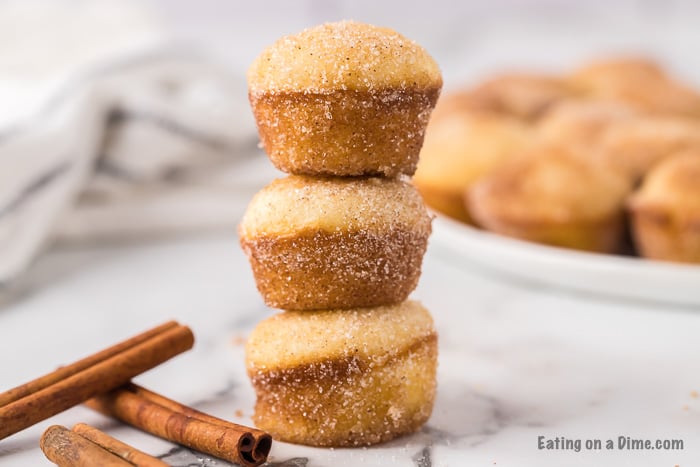 Close up image of mini donut muffins. stacked with cinnamon sticks. 
