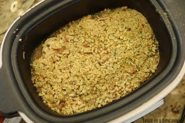 Stuffing mixture on top of the chicken mixture in the slow cooker