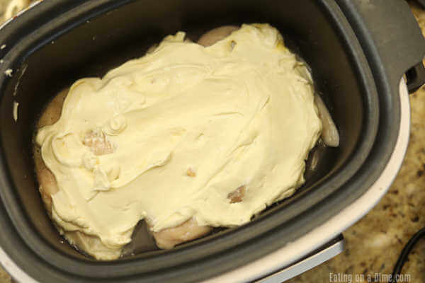 Spreading the cream of chicken soup mixture on the chicken breast in the slow cooker
