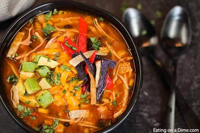 Crockpot Chicken Tortilla Soup Recipe is the best comfort food and it is so simple to make in the slow cooker. This recipe can feed a crowd! Chicken Tortilla in a bowl topped with tortilla chips and diced avocado