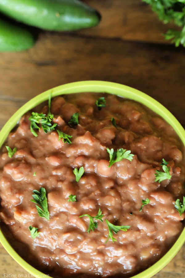 Close up image of refried beans in a green bowl. 