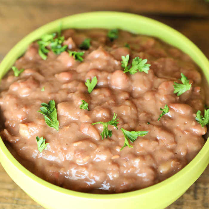 Close up image of refried beans in a green bowl. 
