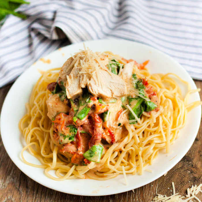 Close up image of Creamy Tuscan Chicken on a plate with pasta. 