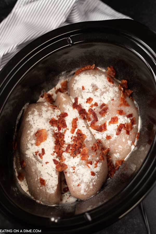 picture of ingredients in crockpot- chicken, ranch seasoning mix, bacon.