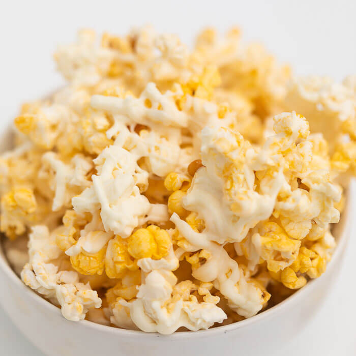 White chocolate covered popcorn in a white bowl. 