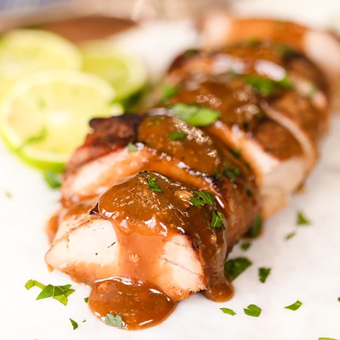 Sliced Pork Tenderloin topped with a honey lime sauce with sliced limes next to it.  