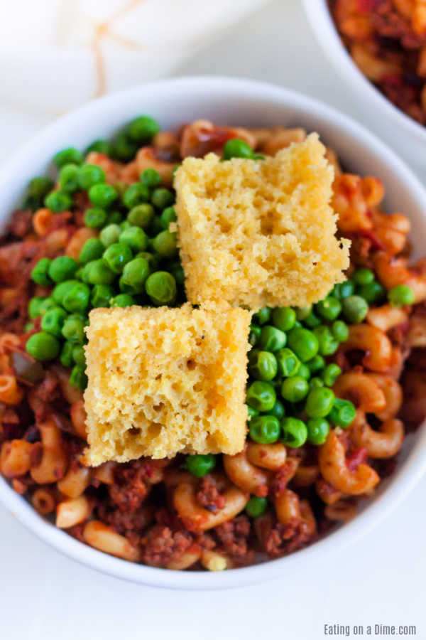 American Goulash topped with peas in a bowl and topped with corn bread
