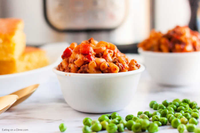 Close up image of goulash in white bowls with a peas on the side. 