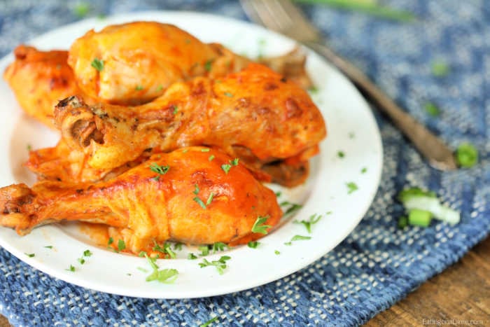 Close up image of buffalo chicken drumsticks on a white plate. 