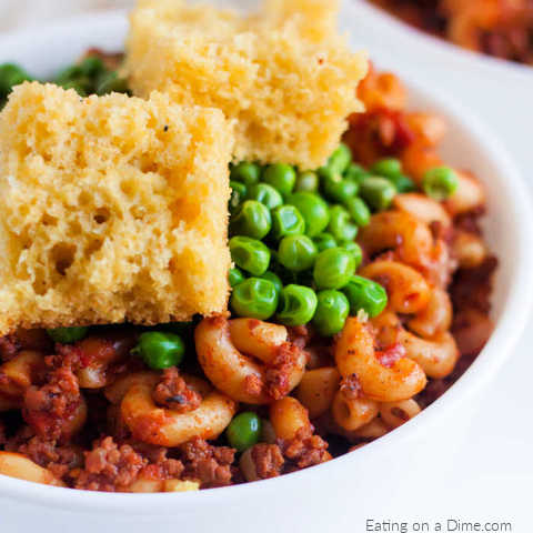 American Goulash topped with peas in a bowl and topped with corn bread