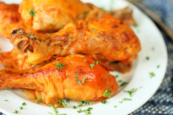 Close up image of buffalo chicken drumsticks on a white plate. 