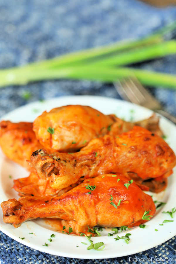 Close up image of buffalo chicken drumsticks on a white plate. 