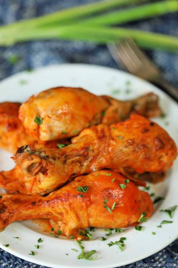Close up image of buffalo chicken drumsticks on a white plate. 