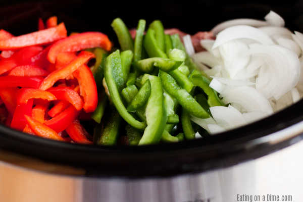 Enjoy a yummy Philly Cheese Steak with little effort when you make this Slow cooker philly cheese steak sandwich recipe. Each bite is flavorful and tasty. Ingredients needed for philly cheesesteaks - red bell pepper, green bell pepper, onion in the crock pot.