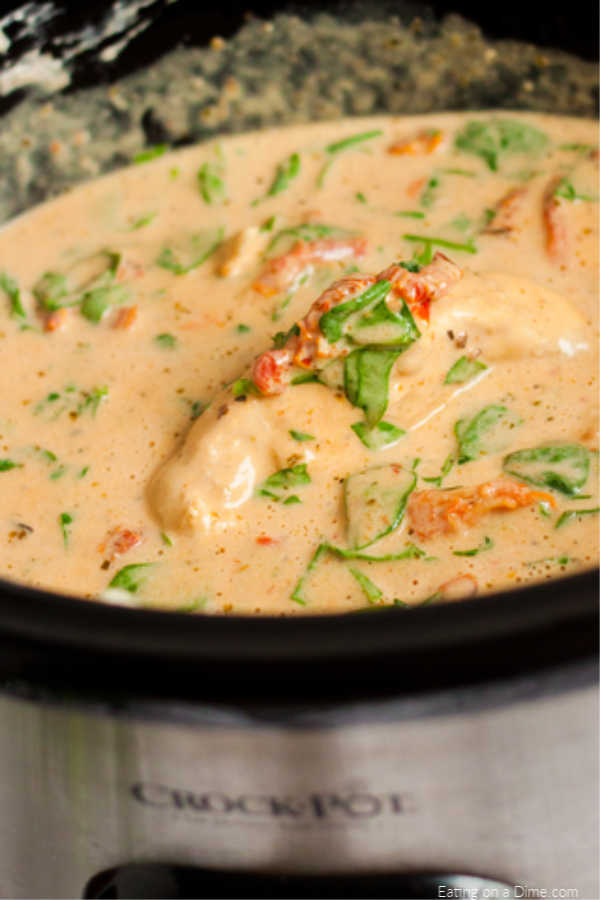 Close up image of creamy tuscan chicken in the crock pot. 