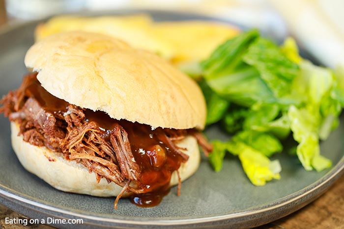 Close up image of shredded brisket on a plate with a side salad. 