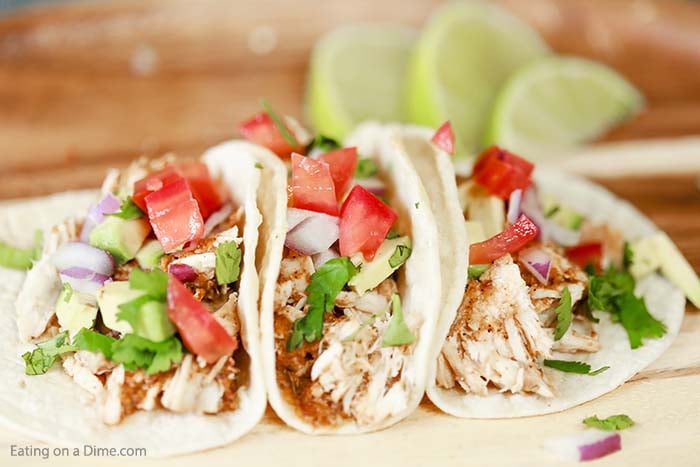 Chipotle chicken tacos on a plate topped with tomatoes, red onion, and cilantro