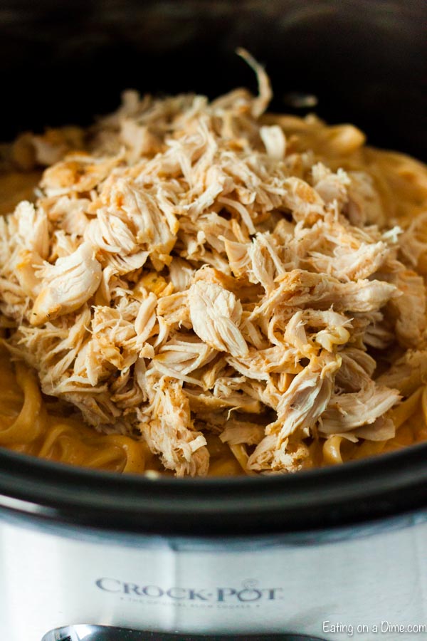Shredded chicken being added back into the creamy mixture in the slow cooker