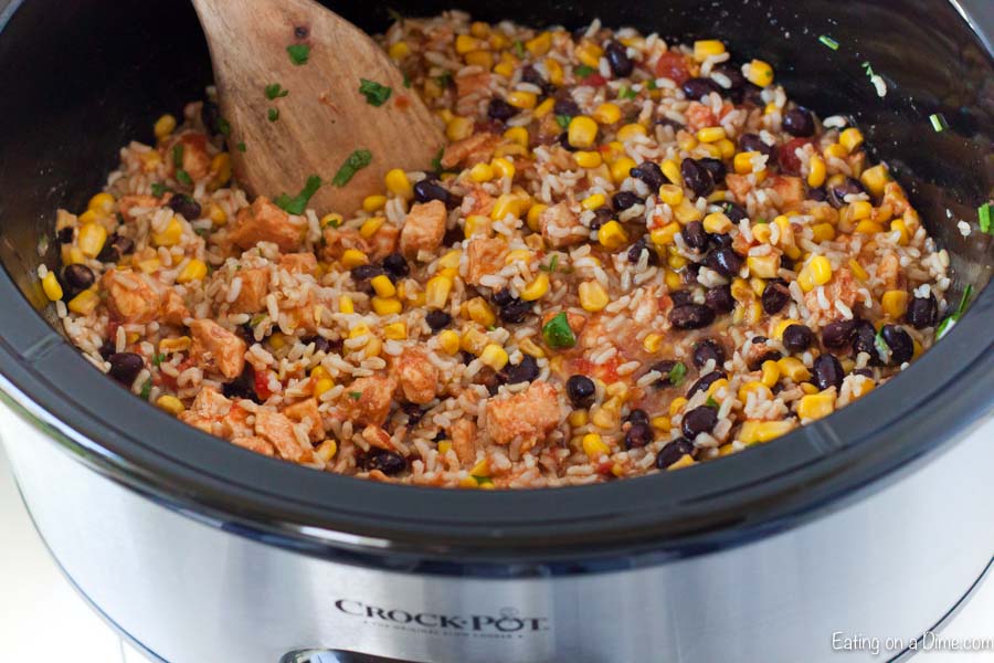 Chicken Burrito Ingredients in a slow cooker with a wooden spoon