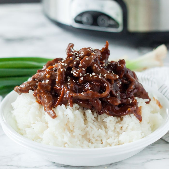 Close up image of Mongolian Beef on a white rice in a white bowl. 