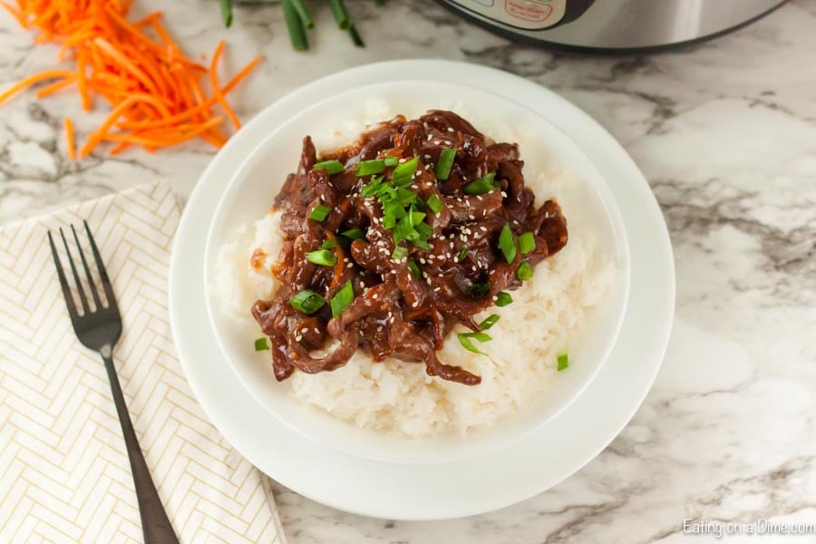 Beef Mongolian on a plate with rice topped with diced green onions