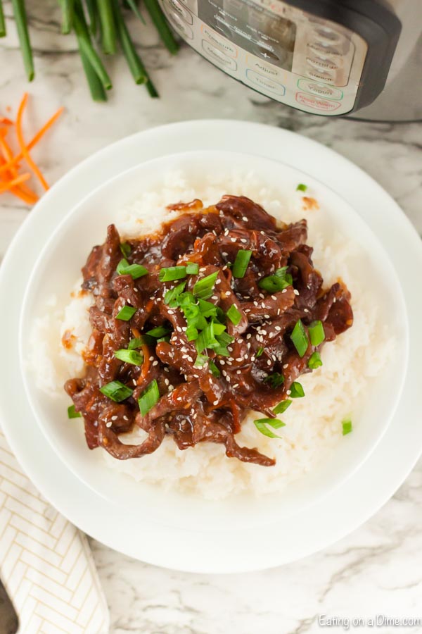 Beef Mongolian on a plate with rice topped with diced green onions